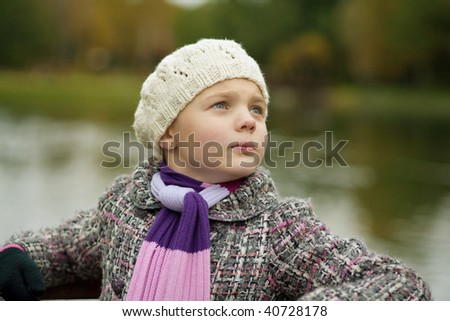 cute pretty young girl in white autumn beret standing with head turned near river in the park