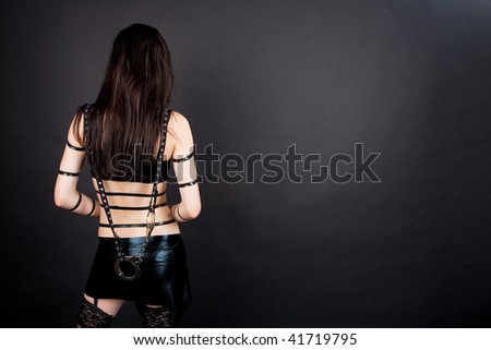 back of young sexy seductive gothic girl standing isolated over gray background