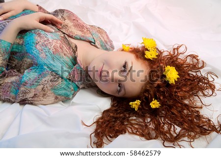 red haired nice caucasian girl with yellow flowers in hair lying with hands lifted and looking up