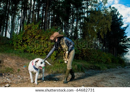 young brunette girl airing her dog and trying to hold it. girl wearing stetson and dog with american flag neckpiece.shoot made on location with flash strobe.