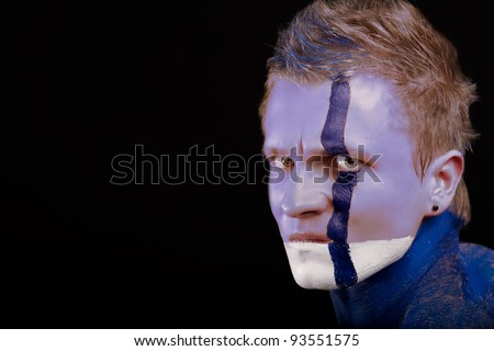 angry looking  caucasian man with body-art  painting and face decoration standing against black background: part of body-art project