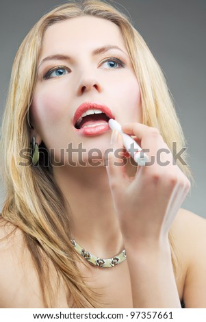 blonde doing makeup with makeup stick looking upwards