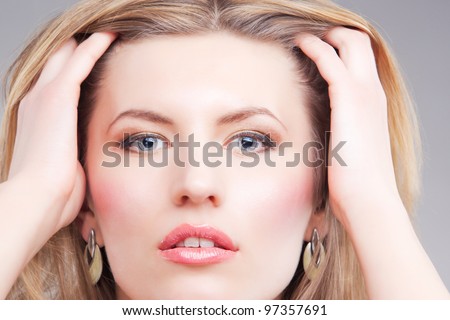 sensual blonde woman having golden jewelry with hands lifted