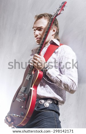 Music and Art Concepts. Portrait of Expressive Male Guitar Player Posing with Electric Guitar Against Gray. Vertical Image