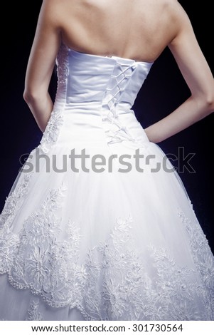 Back View of Bride in Tailored Wedding Dress Against Black. Vertical Image
