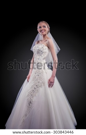 Wedding and Fashion Concept. Portrait of Young Caucasian Female Lady in Tailored Wedding Dress Made to Order Against Black. Vertical Image Composition