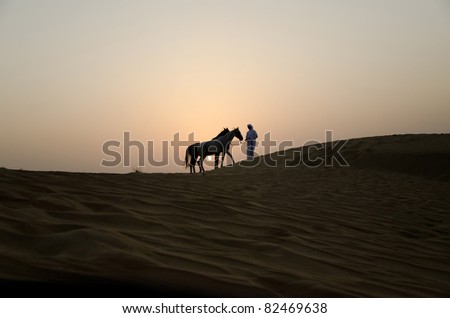 Arab Man with Arabian Horses in the desert during sunset
