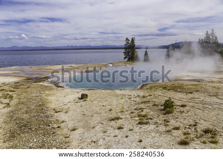 Yellowstone Lake and a pool of steaming hot water near the shore in Yellowstone National Park