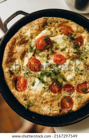 cooked frittata with tomatoes and pieces of meat in a frying pan top view. frittata ready to eat close-up. ready-made egg omelette with greens and cherry tomatoes in a pan. Foto d'archivio © 