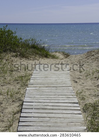 Wooden boardwalk across the sand beach leads to the waters of Lake Michigan.