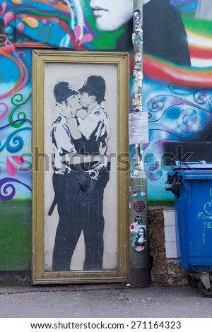 BRIGHTON, ENGLAND - CIRCA APRIL 2015: A photo of Banksy graffiti on the side of a pub in Brighton of two policemen kissing each other in a golden frame