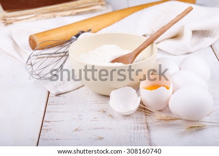 The flour, corolla, cook book and eggs on kitchen table. Cooking