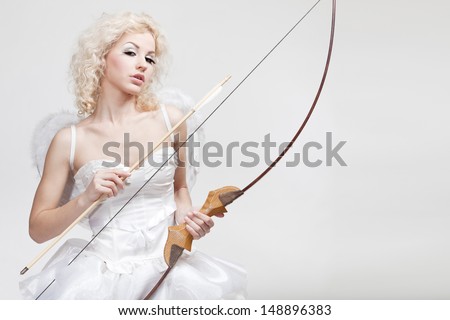 Cupid. Young beautiful blond woman in angel costume holding bow