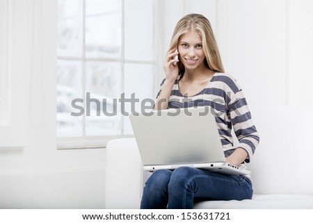 young beautiful blond woman sitting on the couch with laptop