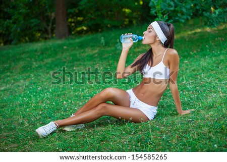 young beautiful brunette sportswoman resting outdoor drinking water