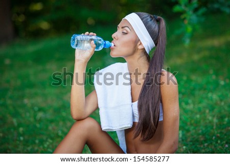 young beautiful brunette sportswoman resting outdoor drinking water