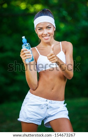 young beautiful brunette sportswoman resting outdoor holding bottle drinking water