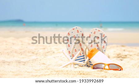 Summer assessorieses. Planing to travel with sunblock and sandal on the beautiful beach and blue sky background. Tropical fashion. Summer Fashion on holiday concept. 