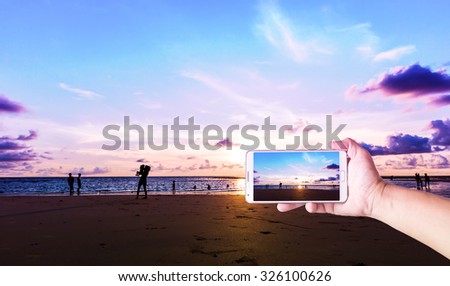 Man photographed sunset and his family on the beach with his Smart phone, Beautiful , sharp images and realistic , Phuket Thailand.