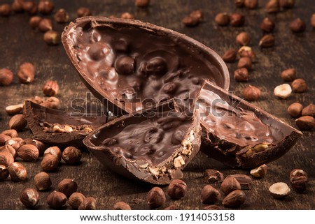 Stuffed chocolate easter egg on a wood table with hazelnuts.