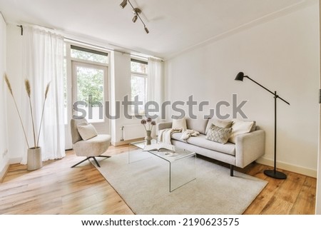 Contemporary minimalist style interior design of light studio apartment with wooden table and chairs in dining zone between open kitchen and living room with white walls and parquet floor Imagine de stoc © 
