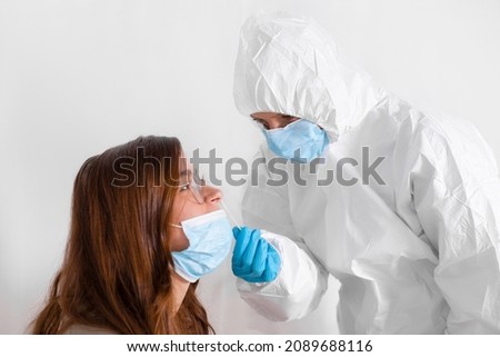 Covid 19 test. Laboratory worker wearing personal protective equipment testing young woman for coronavirus using nasal swab method. Foto stock © 