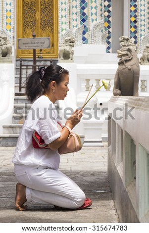 BANGKOK - JUNE 8: An unidentified Thai woman prays at Wat Phra Gaew (the Temple of the Emerald Buddha) on June 8, 2015. The temple welcomes roughly 100,000 visitors a day.