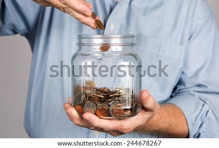 Man drops money into a glass jar for a savings account.