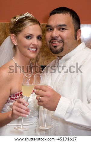 Bride and groom touch champagne filled glasses to toast to each other at their wedding day reception.