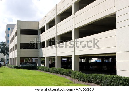 Modern four level parking garage is located next to an office building.