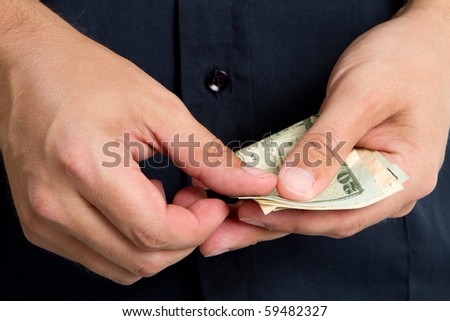 Close up of man\'s hands as he starts to count his money out paying for a purchase.