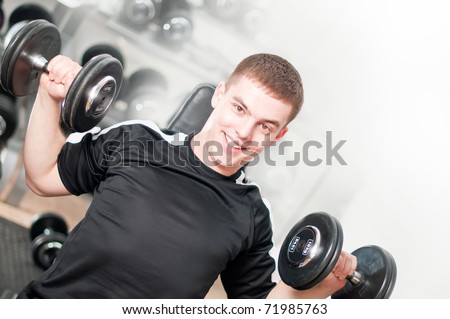 Young man lifting dumbbells in sport club. White background