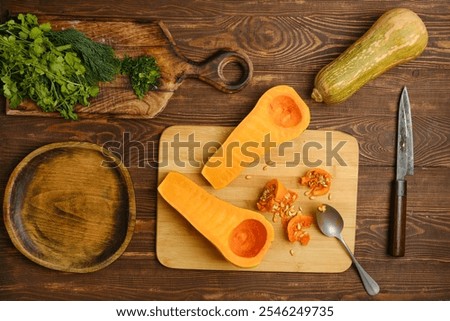 Similar – Image, Stock Photo Halved butternut squash on plate with cutlery and herbs at grey concrete kitchen table background.
