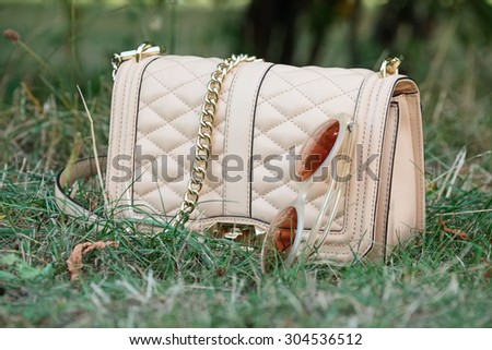 female shoulder bag with sunglasses on the green grass