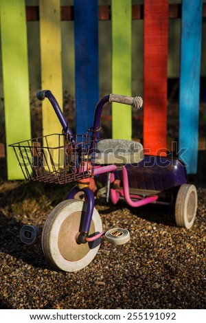 Three wheeled bike in front of colored fence