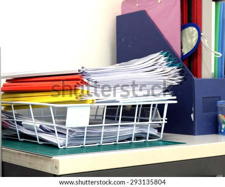 Stack of documents on the desk were located in the training office.