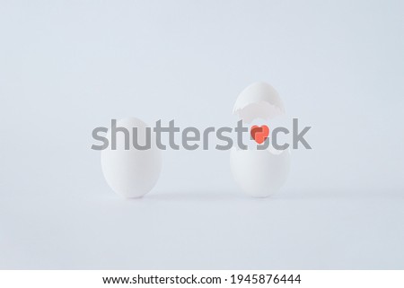 A couple of white eggs  in love on white background. A broken egg with a red heart in the middle. Albino mood eggs. Easter inspiration. Flat lay. Bright Easter minimal concept. Foto stock © 