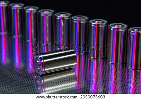 A pack of new modern high-capacity lithium-ion cells. A prototype of new batteries on a steel surface illuminated with red and blue light on a black background Stok fotoğraf © 