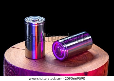 A pair of new modern high-capacity lithium-ion cells. A prototype of new batteries on a tree stump on black background Stok fotoğraf © 