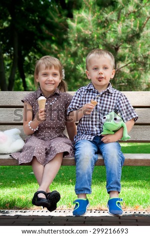 Two children eating ice cream in park looking to camera