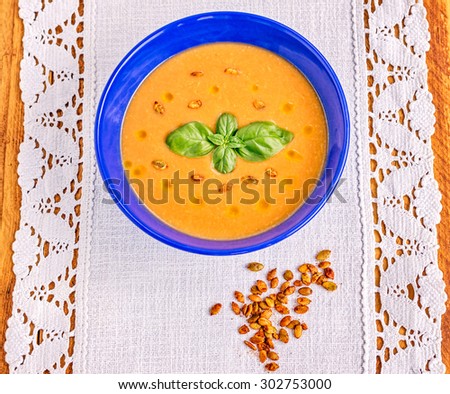 Red lentil cream soup with spiced roasted pumpkin seeds, olive oil and basil leaves garnish