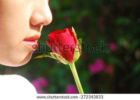 close-up face of asian young women are falling in love. She smelling the red roses in the evening sunshine on the blurred background.