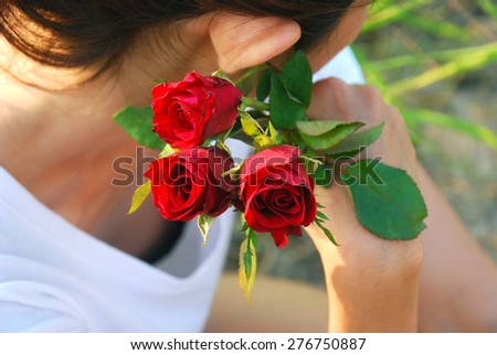 Asian young woman holding a red roses near her face. She thinking and waiting for someone.