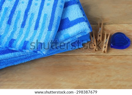 blue stripe towels placed on a wooden background decorated with clothes peg and blue stone glass