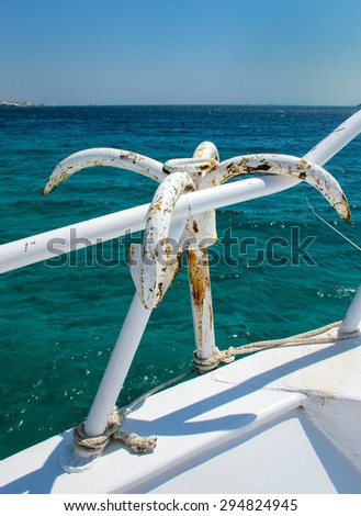 Anchor Hanging on the Handrail of a Yacht\
Calm water of the Red Sea. Anchor hanging on the handrail of a yacht. Horizon over water. Blue summer sky.