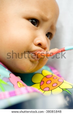 Baby girl with spoon on mouth hate the meal