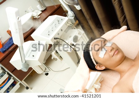 young woman having facial treatment using herbal steamer at beauty clinic