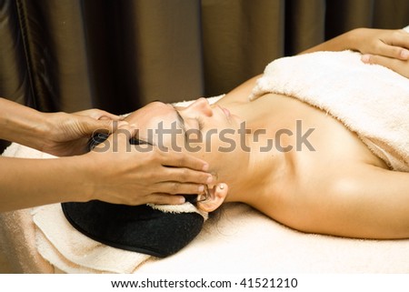 asian young woman having her face massage in facial treatment session at beauty clinic