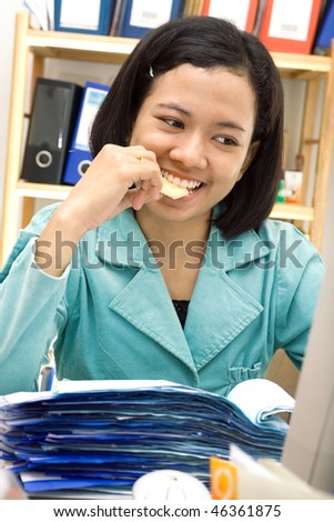 asian female employee eat snack while doing her work