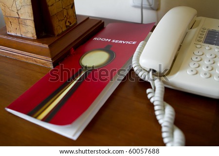 Desk of a hotel guest with room service list and telephone